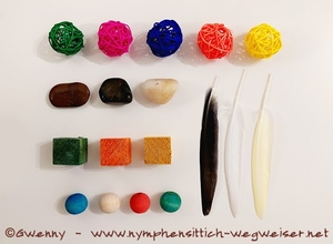 Weidenbälle, Steine, Holzwürfel und -kugeln und Federn in verschiedenen Farben